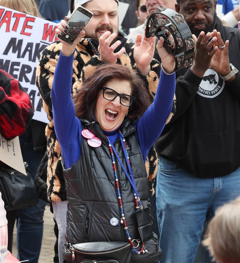 Anna Wilhelmi, head of the DeKalb County Democratic Party, cheers speakers Saturday, April 5, 2025, during a Hands Off! rally at Memorial Park on the corner of First Street and Lincoln Highway in DeKalb. Hundreds of people gathered to protest against various policies of President Donald Trump and his administration.