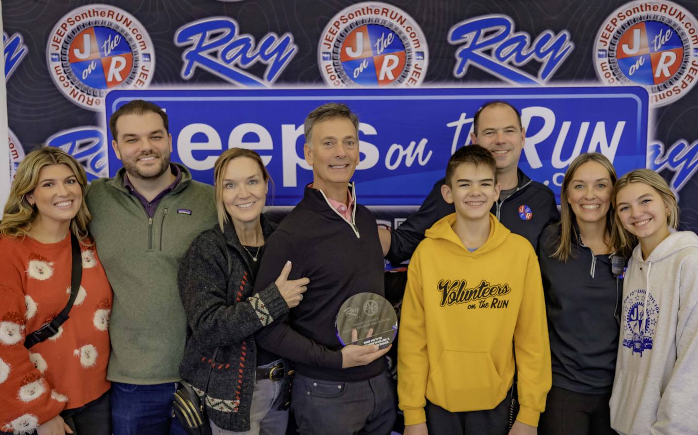 Ray Scarpelli Jr., president and dealer principal of Ray Chrysler Dodge Jeep Ram, holds an award presented to him by Jeeps on the Run for his years of support. With Scarpelli Jr. are (from left) Gabrielle, Ray III and Lisa Scarpelli, and Charlie, Mike, April and Cailyn Missak.