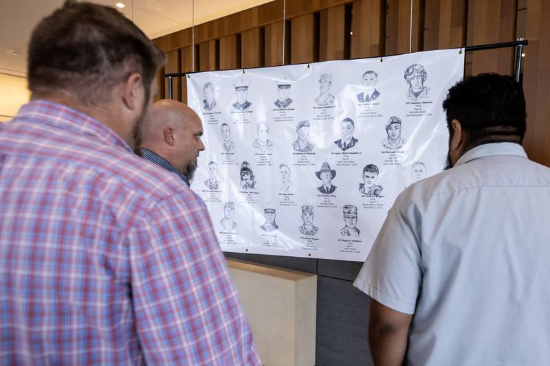 A group of people take a moment to reflect on the image of local heroes, on the ‘Portrait of a Soldier’ exhibit at the Will County Courthouse in Joliet, Illinois, on Sept. 11, 2025.