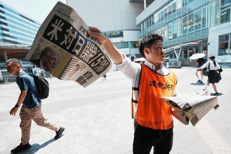 A staff member distributes an extra edition of the Yomiuri Shimbun newspaper reporting that President Donald Trump announced a trade framework with Japan on Tuesday, Wednesday, July 23, 2025, in Tokyo.  The headline reads "U.S.,  a 15% tax on goods imported from Japan." (AP Photo/Eugene Hoshiko)