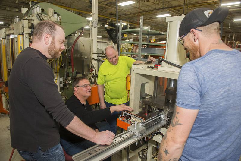 Engineers Toby Kuntzelman (left), Jack Schaefer, Nate Wood and Travis Glenn work to set up a machine for the making of the cooler. Schaefer is a Blissfield consultant, leading the set up.