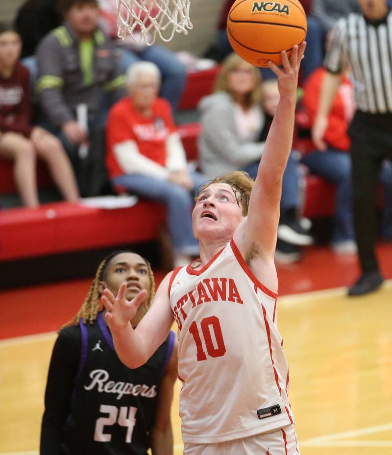 Ottawa's Evan Snook runs in for a layup over Plano's Taron McGowan during the Dean Riley Shootin' The Rock Thanksgiving Tournament on Tuesday, Nov. 26, 2024 in Kingman Gym at Ottawa High School.
