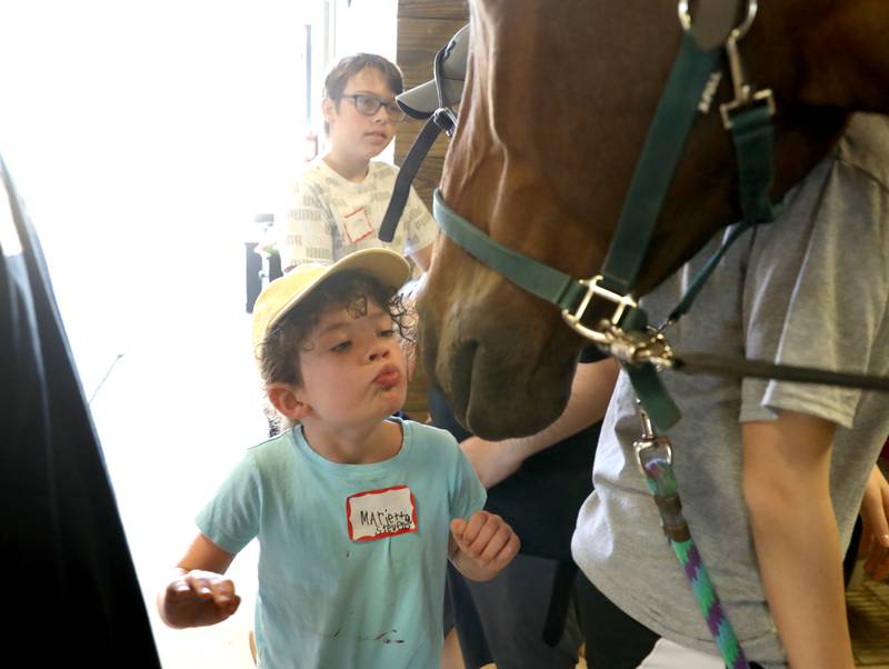 Marietta Stevens, 6, gives a kiss to therapy horse Graham during a day camp at the Happy Hooves Therapeutic Farm in Elburn on Monday, June 27, 2022.