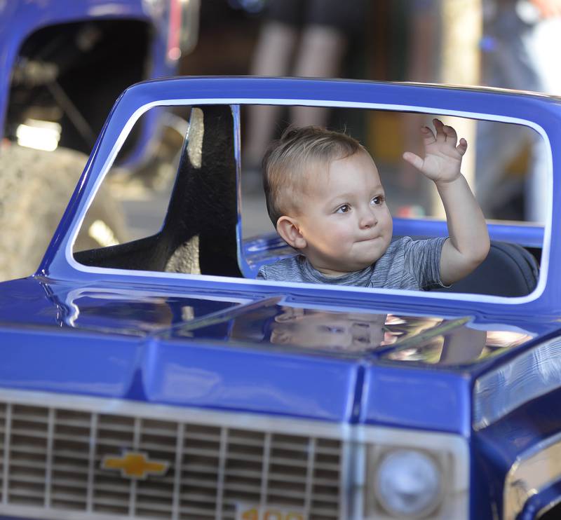 Kaiden Shelton waves to the crowd as they walk by while he sits in a mini Chevy Truck on along Main /St in Streator during The Dream Machine Car Clubs Cruise night Saturday.