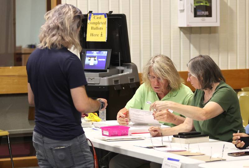 Election judges J O'Halloran (left) and Pat Donlevy help Northern Illinois University senior Dallas Douglass, from DeKalb, get checked in to vote Tuesday, June 28, 2022, at Westminster Presbyterian Church in DeKalb.
