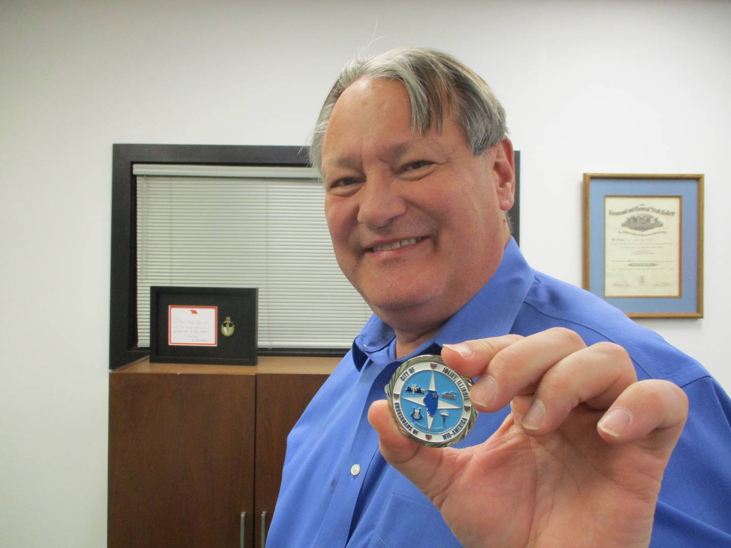 Joliet City Manager holds a commemorate city coin while in his office on March 17, 2022.