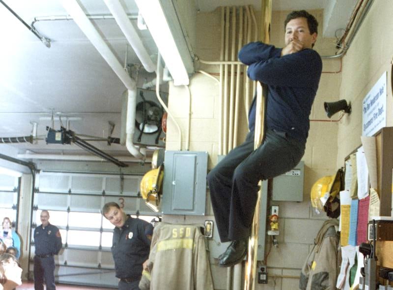 A firefighter slides down a pole at the Sycamore Fire Station on October 4, 1994.