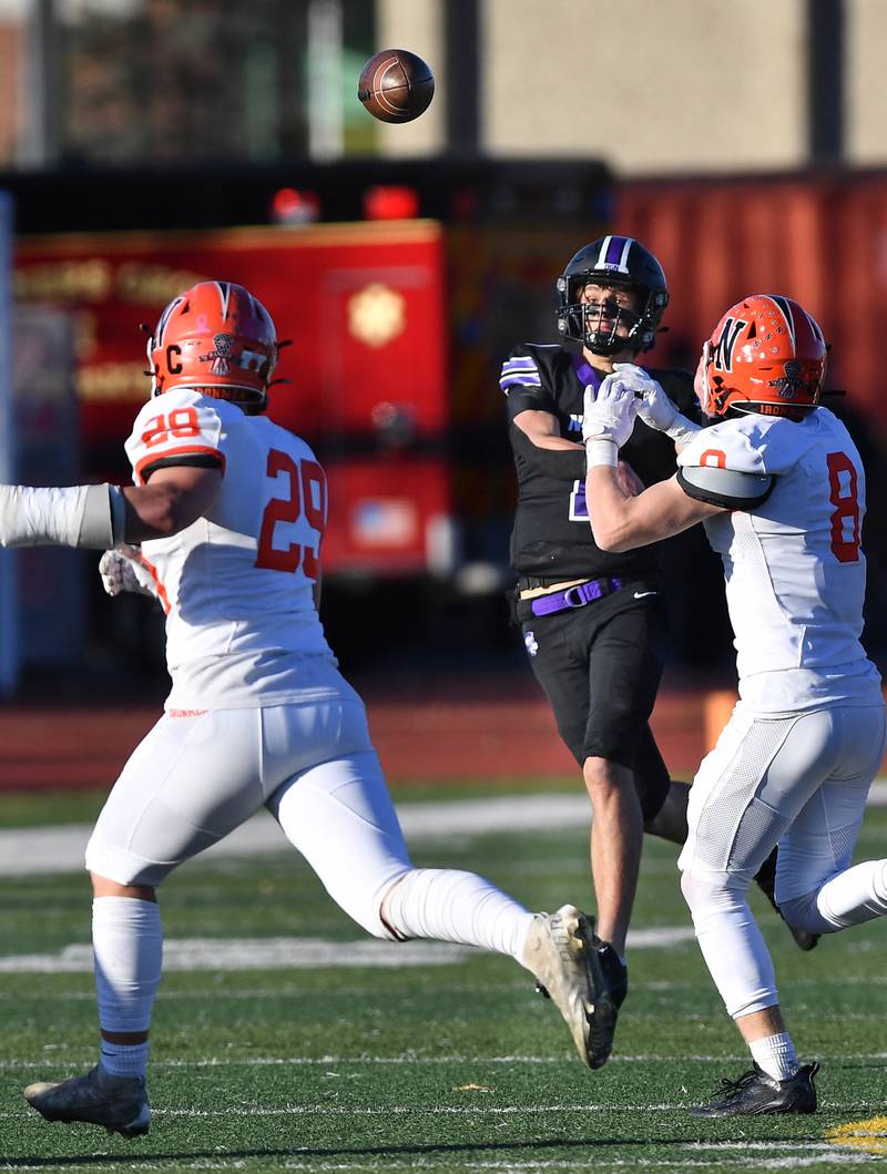 Downers Grove North quarterback Owen Lansu (middle) launches a pass over two Normal Community defenders during an IHSA Class 7A semifinal game on Nov. 18, 2023 at Downers Grove North High School in Downers Grove .
