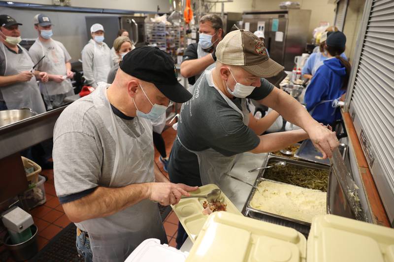 Marc Senffner, left, and Rob Bauer prepares meals for members of the community at the Daybreak Center on Thanksgiving Day in Joliet.