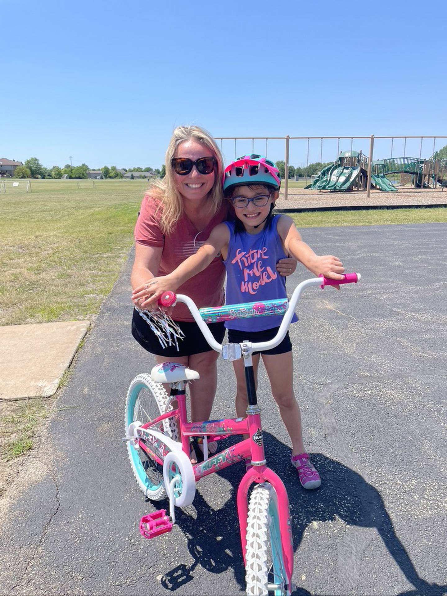 Jennifer Consolino of Homer Glen, a village trustee, said her 8-year-old daughter Genevieve pose for a photo at the recent iCan Bike program, which teaches people with disabilities ages 8 and up to ride a conventional two-wheel bike. The program was held June 14 to June 18, 2021, at Spencer Crossing School in New Lenox.