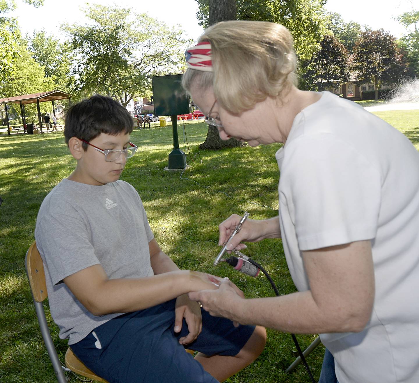 Eli Sphar has an airbrushed tattoo applied by Michelle Orban on Saturday, July 2, 2022, during the Kids Corner event at City Park in Streator.