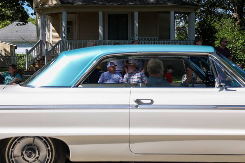 Two paradegoers share a conversation as a classic car passes by during the 104th annual Herscher Labor Day Celebration Grand Parade on Monday, Sept. 1, 2025.