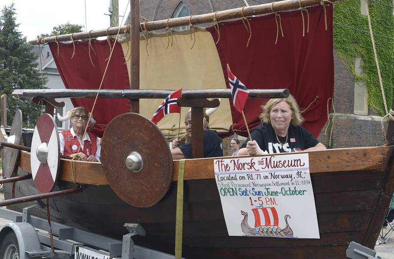 Some members of the Norsk Museum from Norway ride along in a Viking ship during the Community Fest Parade Sunday in Grand Ridge.