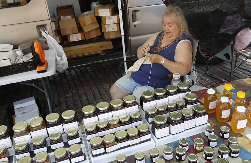 Jan Sosinski of Sosinski's Produce crochets a bag as she waits for customers at the Tuesday Woodstock Farmer's Market on June 24, 2025, around the Historic Woodstock Square.
