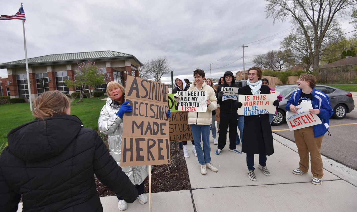 Retired St. Charles North High School teacher Robin Roberts talks with people coming to the District 303 board meeting as she protests with students about the involuntary reassignment of several teachers.