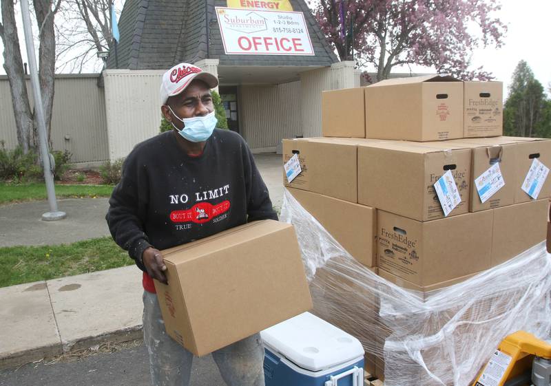 Kevin Green with DeKalb County Community Gardens carries a box of food to a car at Suburban Apartments in DeKalb Wednesday during a food distribution by DCCG at the complex.