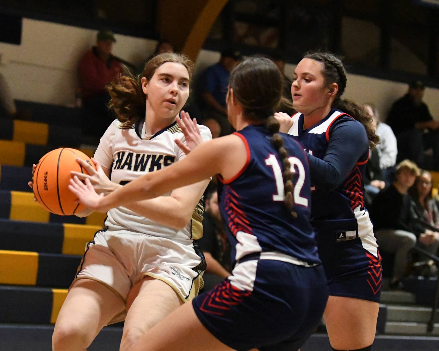 Hiawatha's Brielle Molloy (21) tries to get around Our Lady of The Sacred Heart teammates Jackie Whalen and Angelina Whalen during the game on Monday Dec. 22, 2025, held at Hiawatha High School.