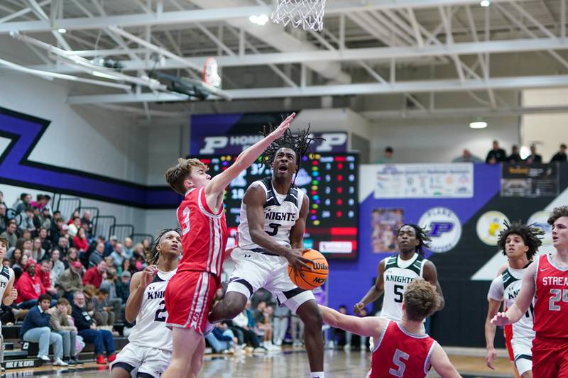 Kaneland's Marshawn Cocroft (3) drives to the basket against Streator's Nolan Ketcham (3) and Isaiah Weibel (5) during a semi-final basketball game in the 61st annual Plano Christmas Classic at Plano High School on Friday, December 27, 2024.