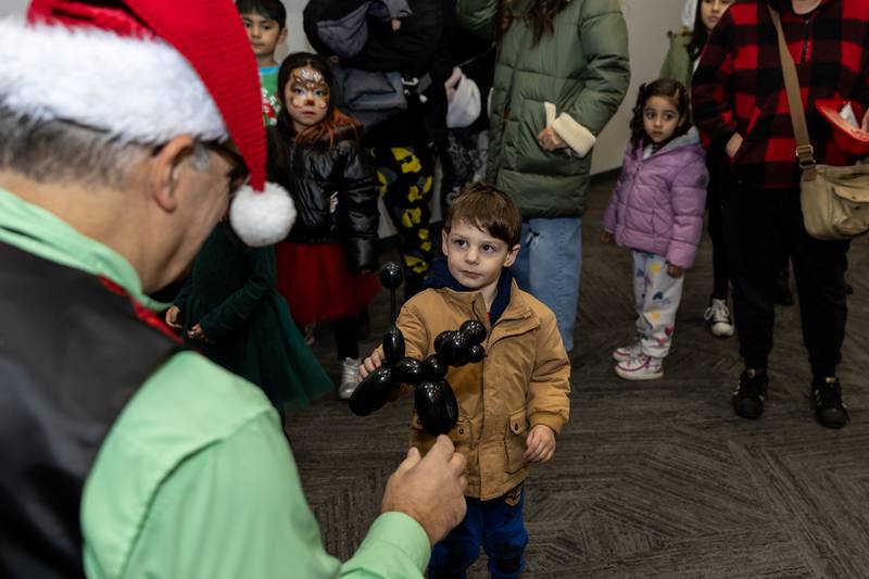 Crest Hill resident Dean Nestor gets a balloon dog made by Frank Birdsall of Sparkles Entertainment during Winterfest at Crest Hill City Center on Nov. 30, 2024.