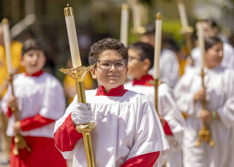 Server Carlos Sola walks in the Corpus Christi procession Sunday, June 2, 2024, between three La Salle churches.