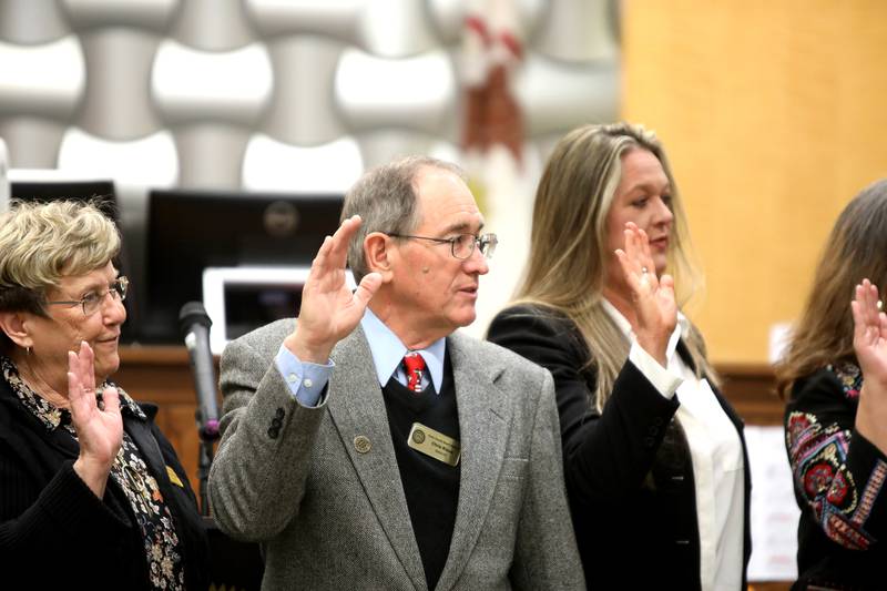 Kane County Board member Chris Kious (center) takes the oath during a swearing in ceremony for newly and re-elected board members at the Kane County Circuit Court in St. Charles on Monday, Dec. 5, 2022.