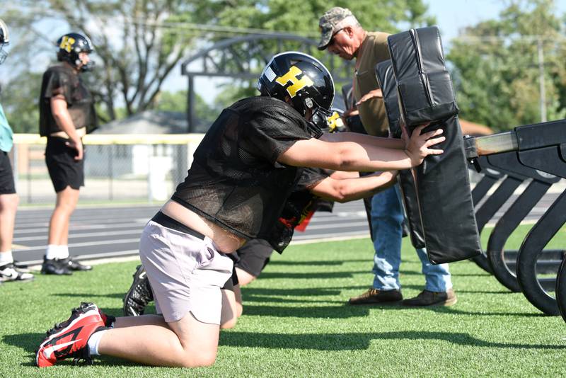 Herscher's Caden Latty, left, and his teammates perform a drill on the blocking sled under the instruction of assistant coach John Wakey at football practice Wednesday, Aug. 13, 2025.