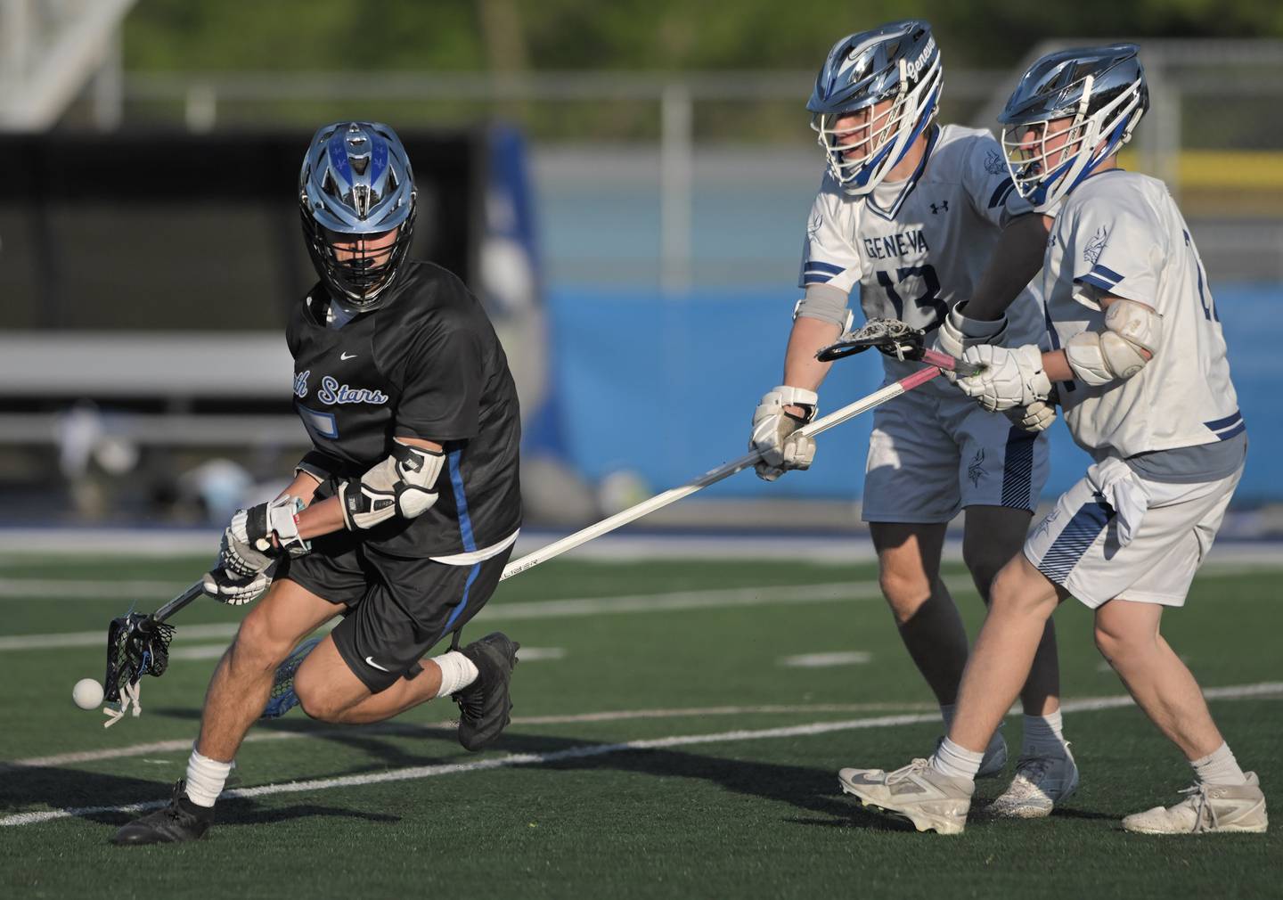 St. Charles North’s Daniel Escaro loses the ball to the defense of Geneva’s Lukas Costello and Kai Costello, right, in a boys lacrosse game in Geneva on Friday, May 15, 2026.