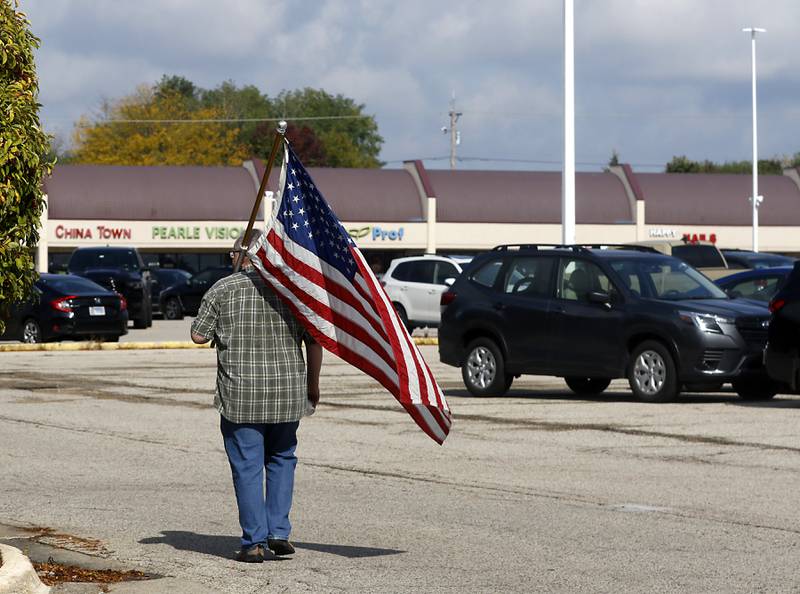 A protester carries his flag as he walks back to his car after the "No Kings” protest rally on Saturday, Oct. 18, 2025, along Route 31 in McHenry. The protest drew thousands of protesters to the area to protest the policies of President Donald Trump.