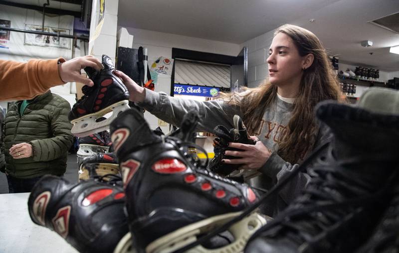 Employee Madison Shines hands skates to open skate attendees at Crystal Ice House in Crystal Lake on Friday, Jan. 3, 2025.