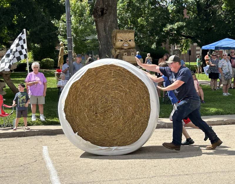 Sawyer Marceau of Polo and Zakkary West of Mt. Morris roll a large round straw bale down Wesley Avenue and across the finish line in Mt. Morris during the Straw Bale Race at Strawfest on Saturday, Aug. 23, 2025. The 17-year-olds won the event with the fastest time of 9.36 seconds.