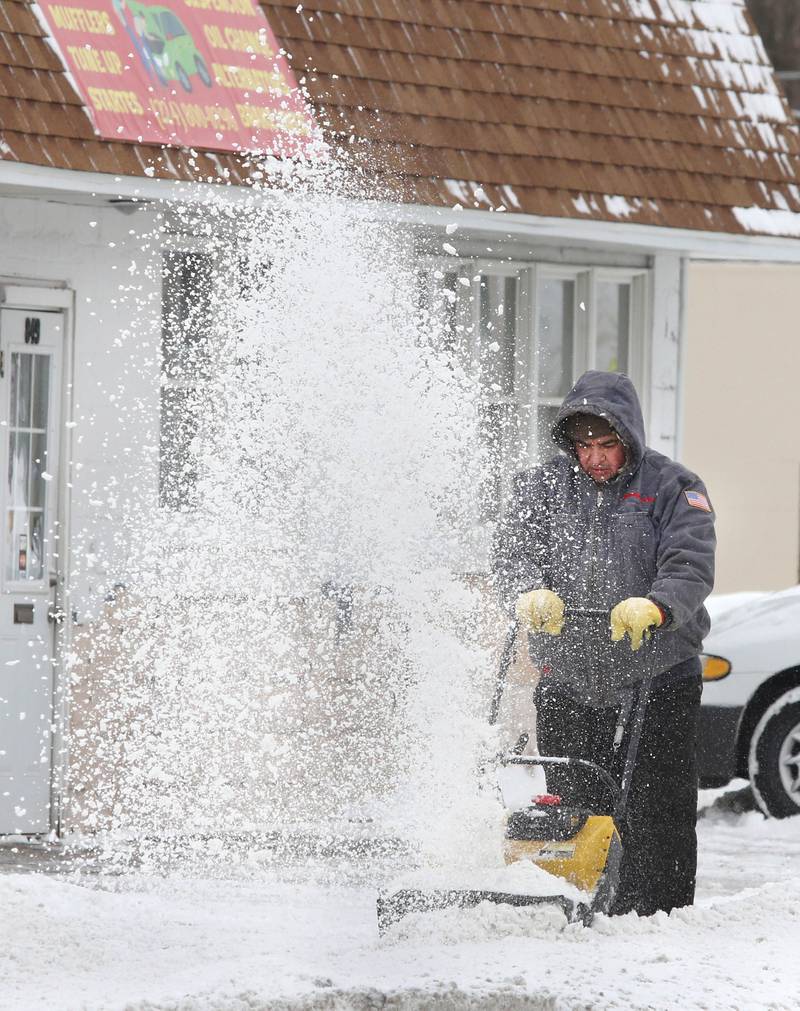 A worker clears the snow in front of Taller America Compete Auto Care Wednesday, Feb. 2, 2022, in DeKalb. Snow fell overnight and into Wednesday across DeKalb County.