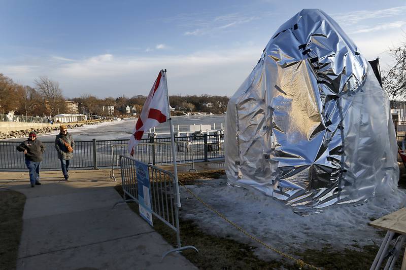 Two ladies walk past covered block of snow to protect it from rain and heat on Thursday., Jan. 30, 2025, Snow carvers have started carving their 15 massive snow sculptures on Thursday, Jan. 30, 2025, for America’s Snow Sculpting Invitational during Winterfest in Lake Geneva. Winterfest, runs through Feb, 2, 2025. The warm and rainy weather has slowed down the carving of the snow.