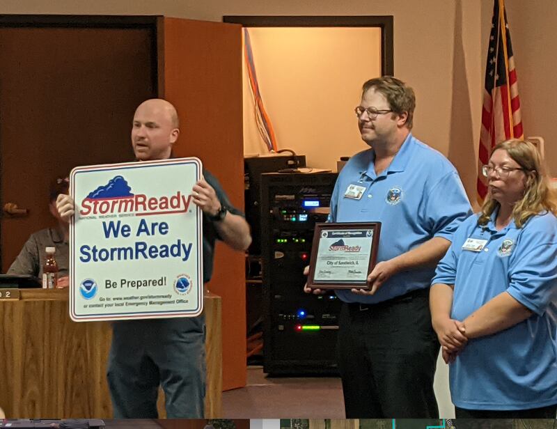During the Sept. 16 Sandwich Committee-of-the-Whole Council meeting, Mike Bardou of the National Weather Service presents a StormReady sign to the city. Looking on are Sandwich Emergency Management Agency Assistant Director Tim Keierleber, left, and volunteer Caroline Thomas, right.