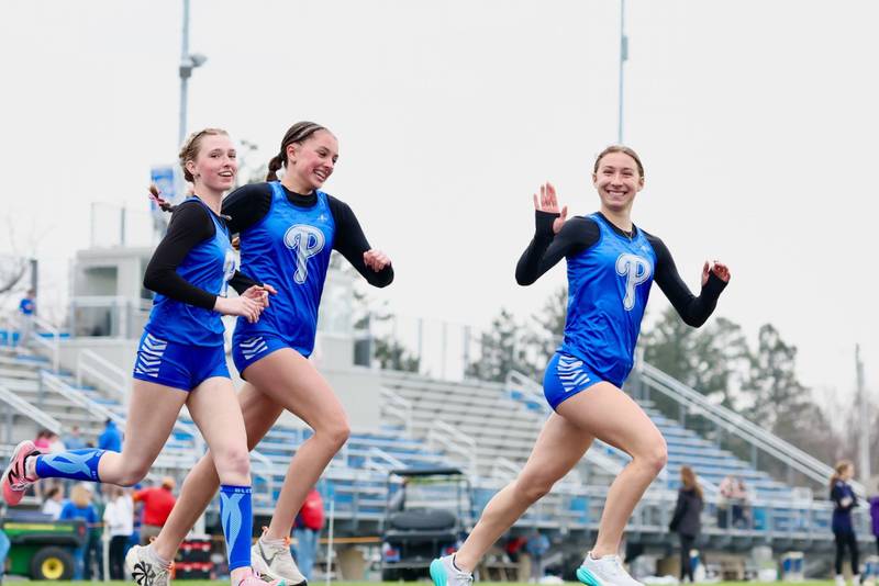 Princeton's Ruby Acker is all smiles running the 1,600 meters in Thursday's Howard-Monier Invite along with teammates Payton Frueh (left) and Alexandra Waca.