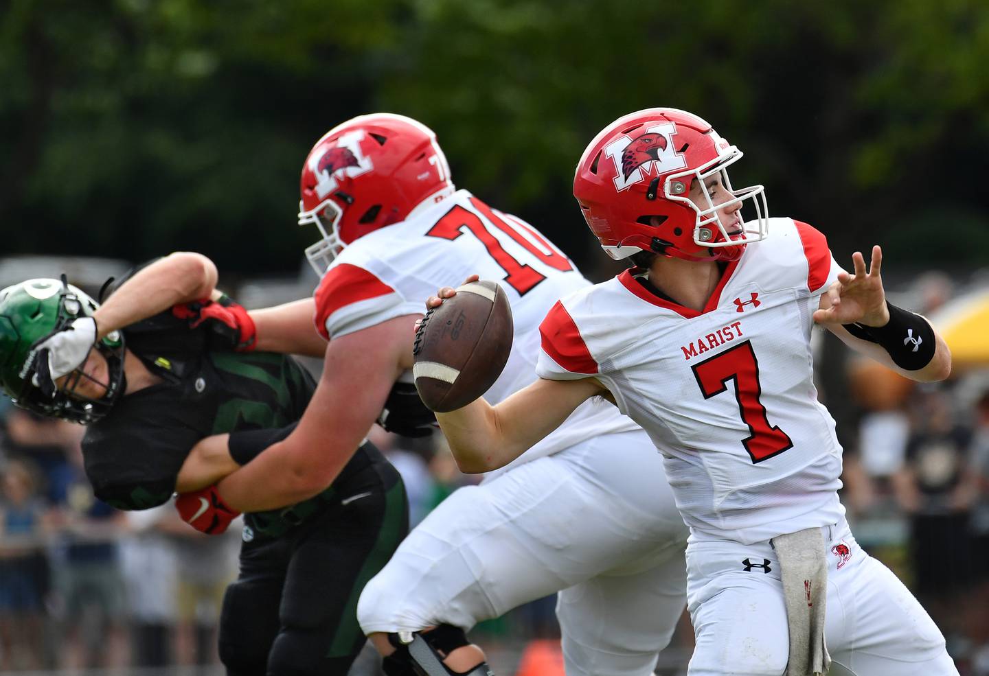 Marist quarterback Owen Winters (7) launches a pass behind a block from teammate Rico Schrieber (70) during a game on Aug. 26, 2023 at Glenbard West High School in Glen Ellyn.