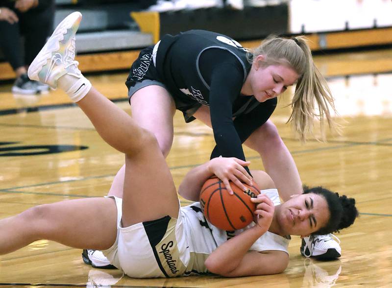 Kaneland's Kendra Brown and Sycamore's Monroe McGhee fight for a loose ball during the Class 3A regional final game Friday, Feb. 17, 2023, at Sycamore High School.