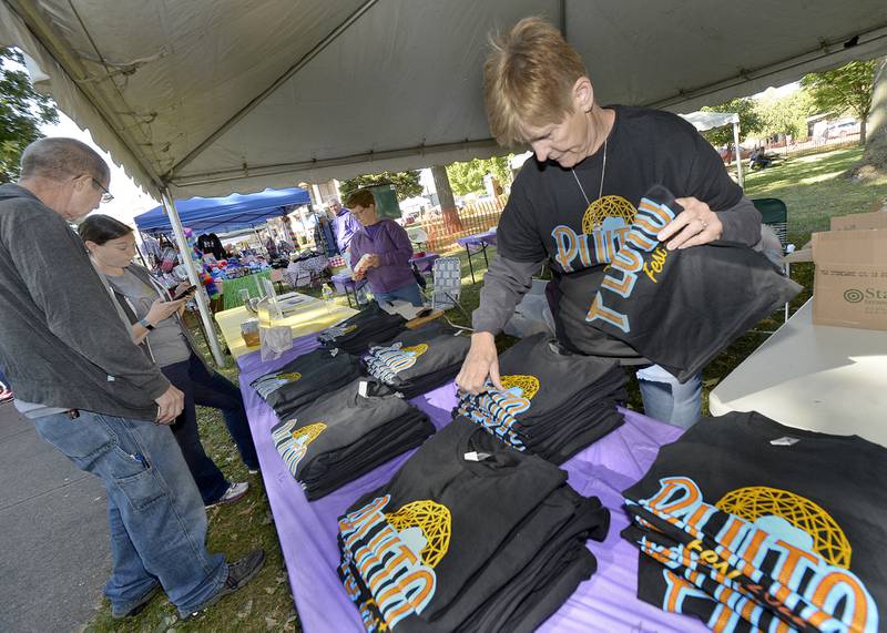 Karyn Dzurison with the Hardscrabble Lions Club sorts Pluto T-shirts Saturday, Sept. 24, 2022, at the club's vendor booth during Pluto Fest at City Park in Streator. The Hardscrabble Lions Club sponsor the event.