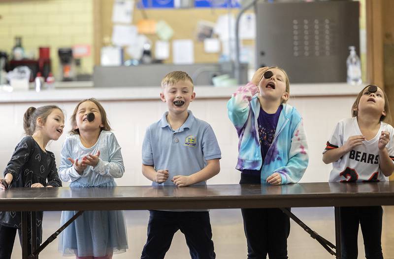 St. Anne’s students work to move an Oreo across from their forehead to the mouth Tuesday, Jan. 28, 2025, at the Dixon school. The Minute To Win It game really had no winners other than those who got to eat the cookie after.