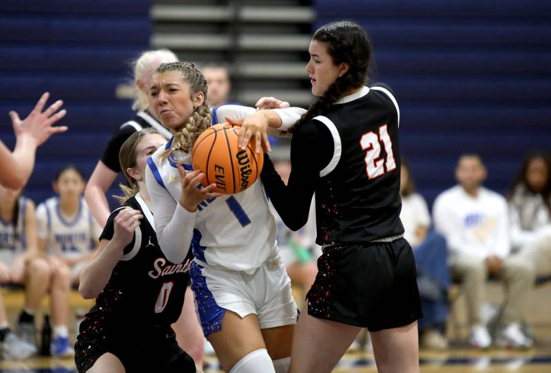 Wheaton North’s Adeline Sutton squeezes through a pair of St. Charles East defenders during a game on Tuesday, Dec. 10, 2024 in Wheaton.