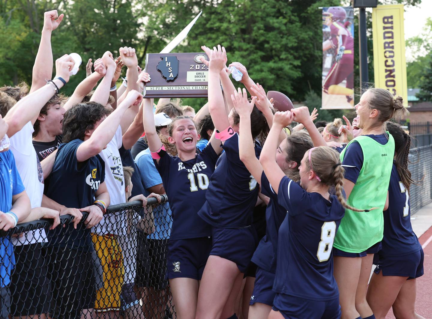 IC Catholic's Ashley Zwolinski (10) holds the championship plaque as the team celebrates their victory with their fans after the IHSA Class 1A girls soccer super-sectional match between Richmond-Burton and IC Catholic at Concordia University in River Forest on Tuesday, May 23, 2023.