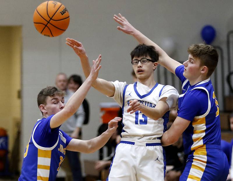 Woodstock's Joesph Nitz (center) passes the ball out of the double team of Johnsburg's JT Schmitt (left) and Jayce Schmitt (right) during a Kishwaukee River Conference basketball game on Friday,  Feb. 14, 2025, at Woodstock High School.