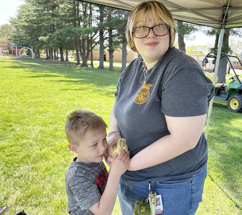 Oregon High School FFA student Kerrie Diaz, holds a gosling for pre-kindergartener Kandyn Larson to pet during at the FFA petting zoo on Friday, May 9, 2025. FFA kids also brought their tractors to the Oregon Elementary School for grade school students to explore.