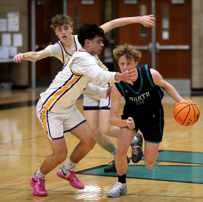 Woodstock North's Conlan Leese (right) pushes the ball up the court against the defense of Hononegah's Oba Fasalojo (left) and Hononegah's Cole Warren (center) during the 2025 Hoops for Healing tournament basketball game on Wednesday, Nov. 26, 2025, at Woodstock North High School.