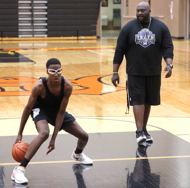 Jay Moore, founder of TRUTH Basketball Academy and an assistant basketball coach at DeKalb High School, watches Gabe Crump, 15, from DeKalb, work in a dribbling drill Tuesday, June 25, 2024, during a session at the school.