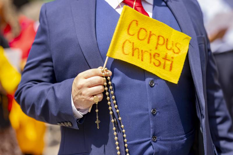 A participant in the Corpus Christi procession holds a flag and prayer beads Sunday, June 2, 2024, during the three-parish walk in La Salle.
