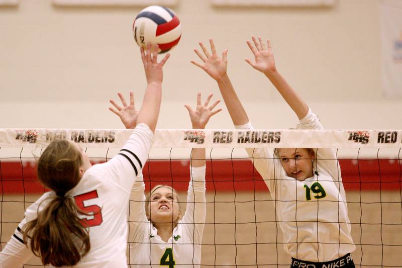 Crystal Lake South’s Bella Toniolo, center, and Logan Georgy, right, block against Huntley’s Elizabeth Williams, left, in varsity volleyball at Huntley Tuesday.