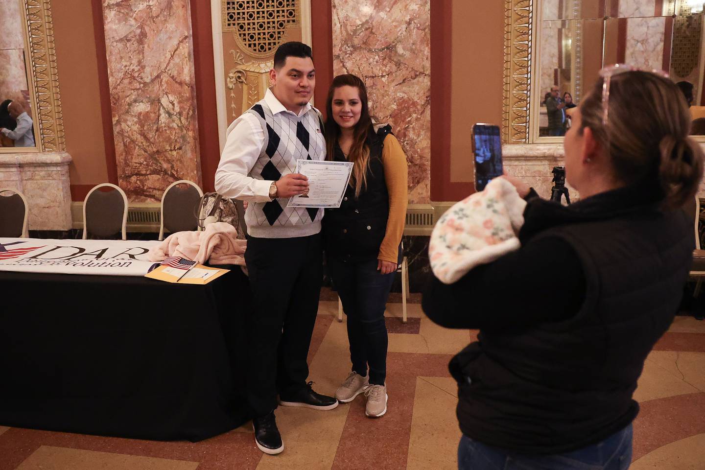 Newly appointed U.S. citizen Jose Martinez, from Mexico, poses with his wife Dulce poses for a photo with his Certificate of Naturalization during the Special Naturalization Ceremony held at the Rialto Square Theatre in downtown Joliet on Tuesday, April 23, 2024.