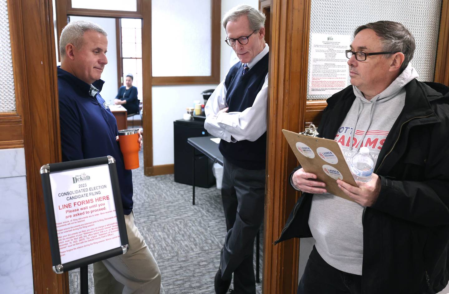 DeKalb City Council Ward 5 alderman Scott McAdams (right) waits for candidate filing to open as mayor Cohen Barnes (left) and city manager Bill Nicklas watch the door Monday, Dec. 12, 2022, at City Hall. McAdams, who is running for re-election, was among the first candidates in line Monday at 8:30 a.m. when filing opened at City Hall.