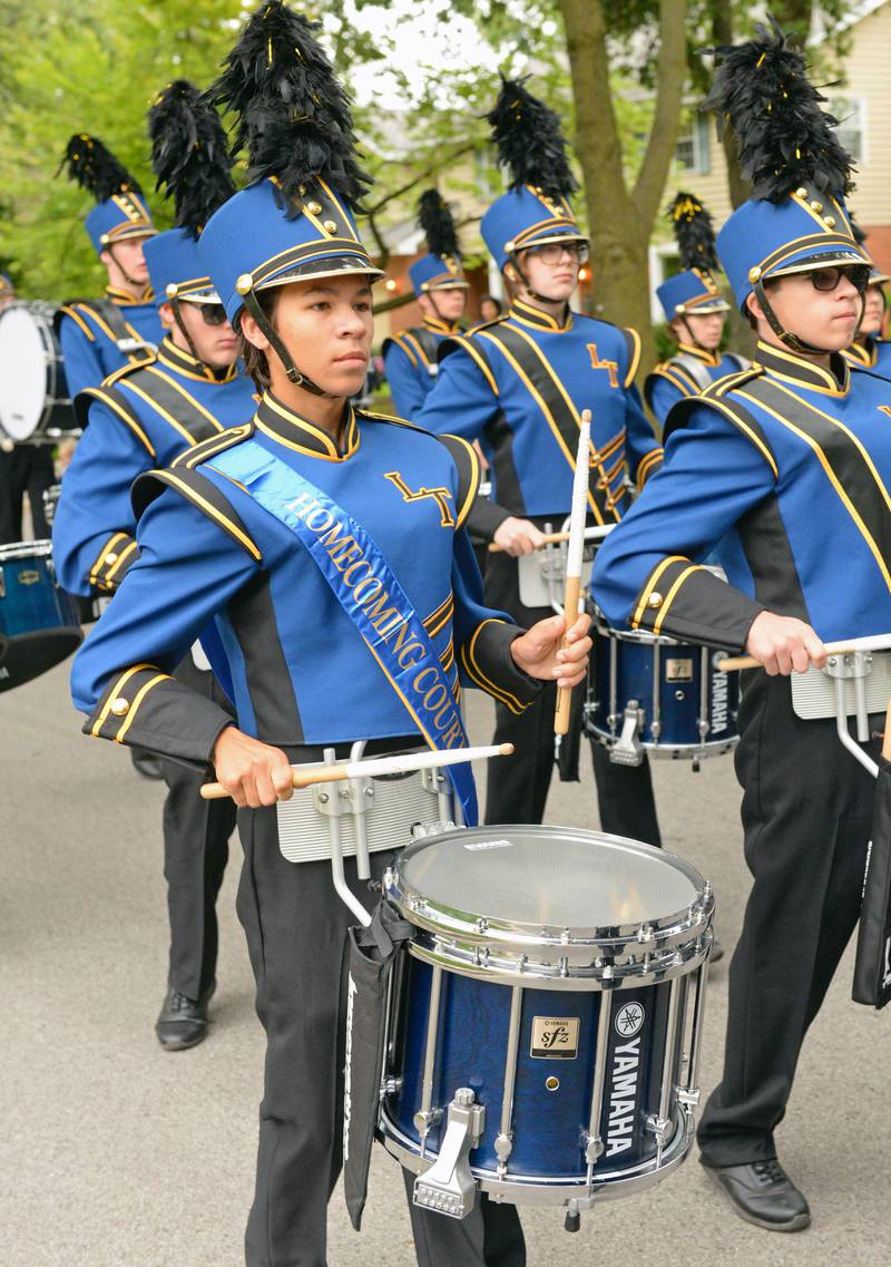 A member of the Lyons Township High School homecoming court (left) does double duty with the marching band as students and alumni march through La Grange heading for Western Springs in the annual homecoming parade on Saturday, Sept. 24, 2022.