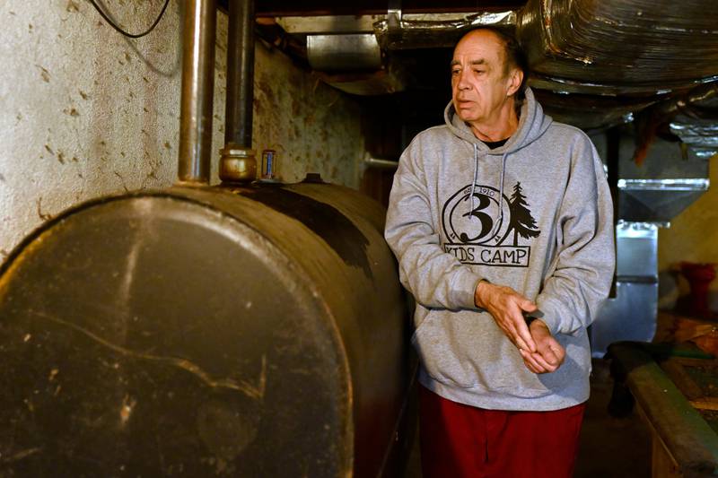 Mark Bain, who is part of the Low Income Home Energy Assistance Program, rubs his hands together as he checks the level on his oil at home in hopes that he will have enough oil to outlast the shutdown, in Bloomfield, Conn., Monday, Oct. 27, 2025. (AP Photo/Jessica Hill)